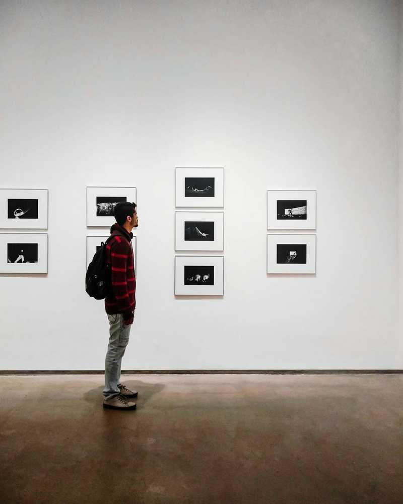 Jeune homme dans un musée regardant des photographies. 